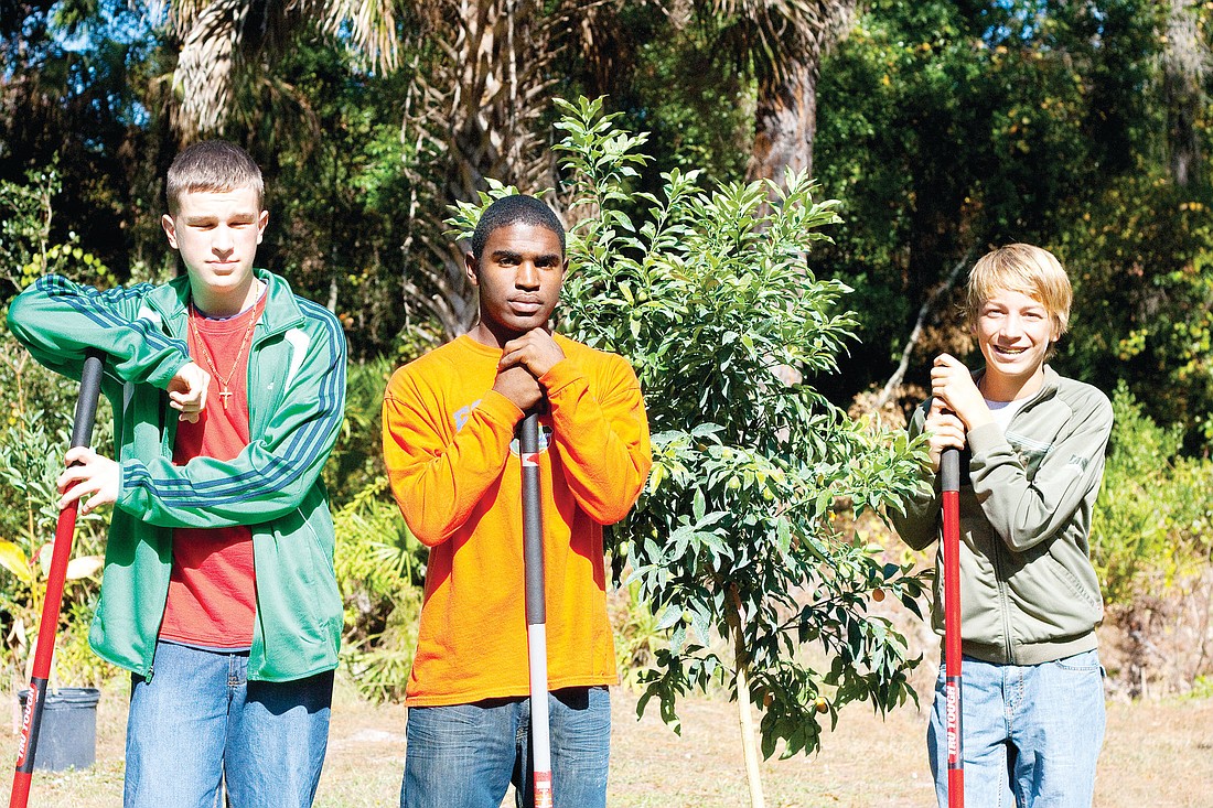 Jerzy Misztal, of Indian Trails, and Saevonne Fleming and Zane Arrington, of Matanzas High, helped plant fruit trees at the garden. PHOTO BY SHANNA FORTIER