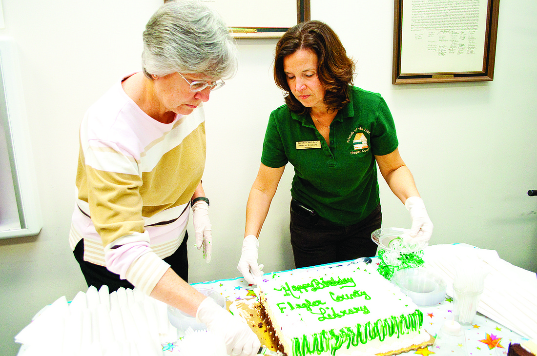Barbara Bohres and Dianne LaVerne serve cake for the library's birthday.