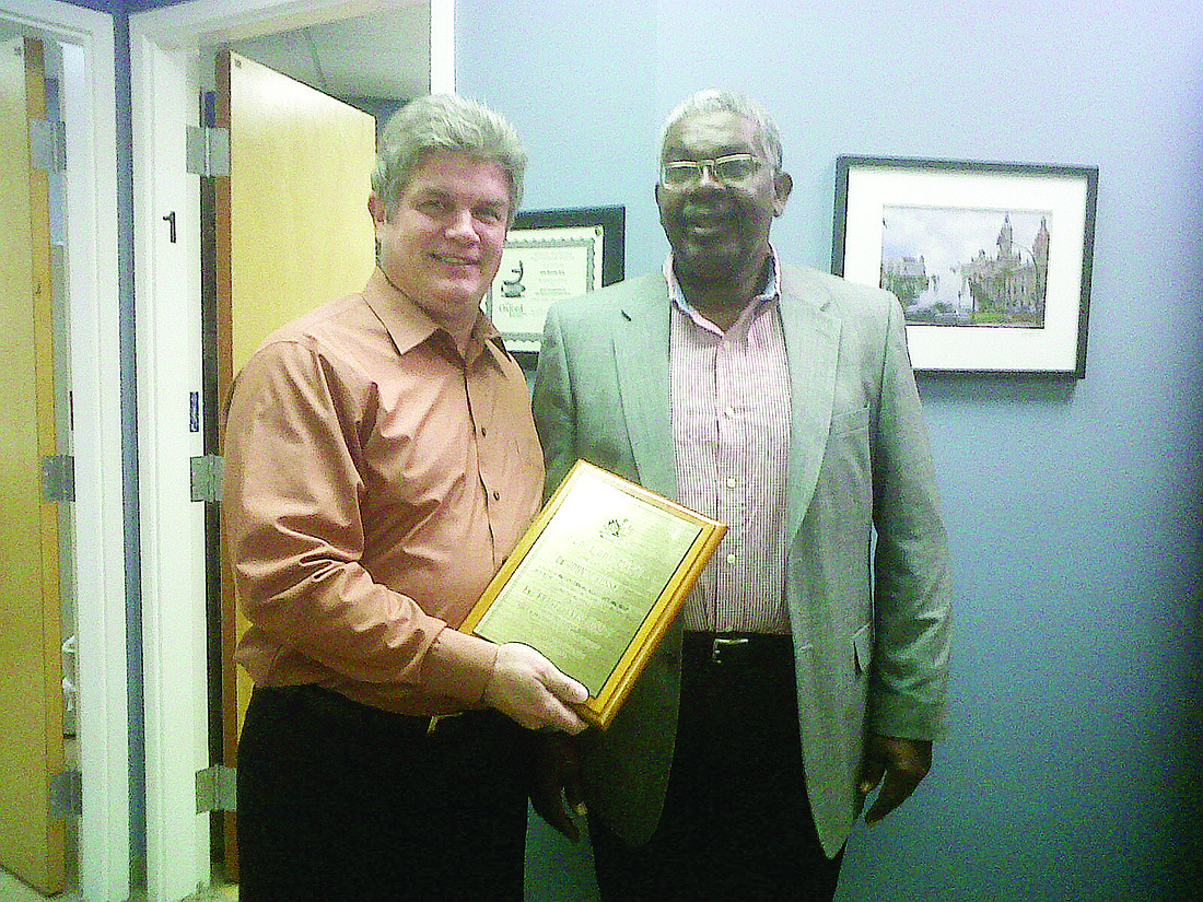 Dr. John Russell receives a plaque from Frantz Yves Joseph. COURTESY PHOTO