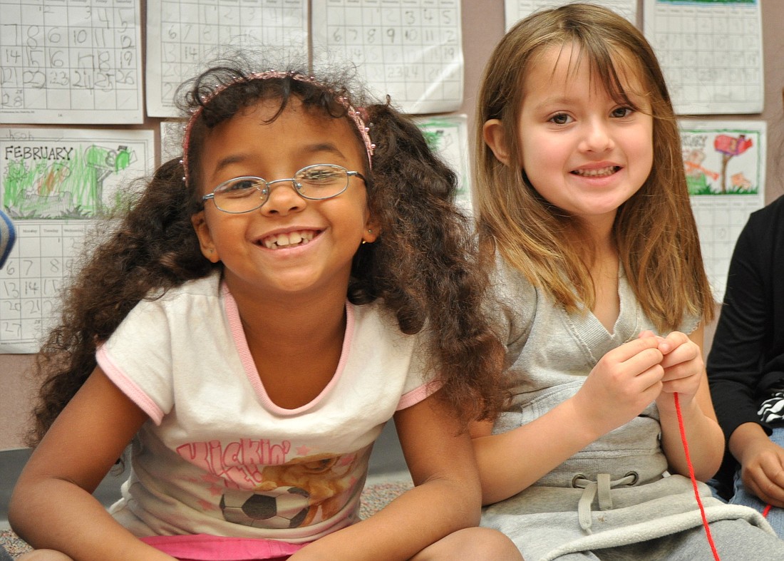 Jaisa Ferlazzo and Samantha Mendoza, kindergarten students at Old Kings Elementary, celebrate the 100th day of school by making Froot Loop necklaces. PHOTO BY SHANNA FORTIER