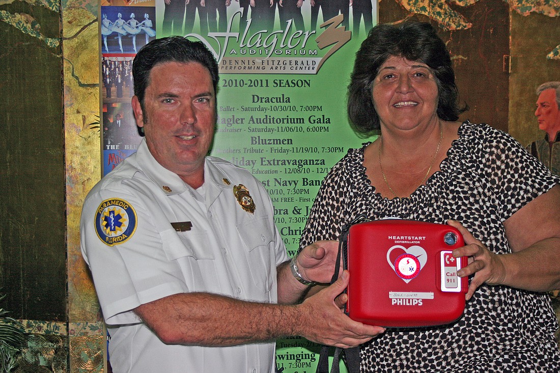 Flagler County Fire Rescue Chief Don Petito hands an automatic external defibrillator to Lisa McDevitt, director of the Flagler Auditorium. COURTESY PHOTO
