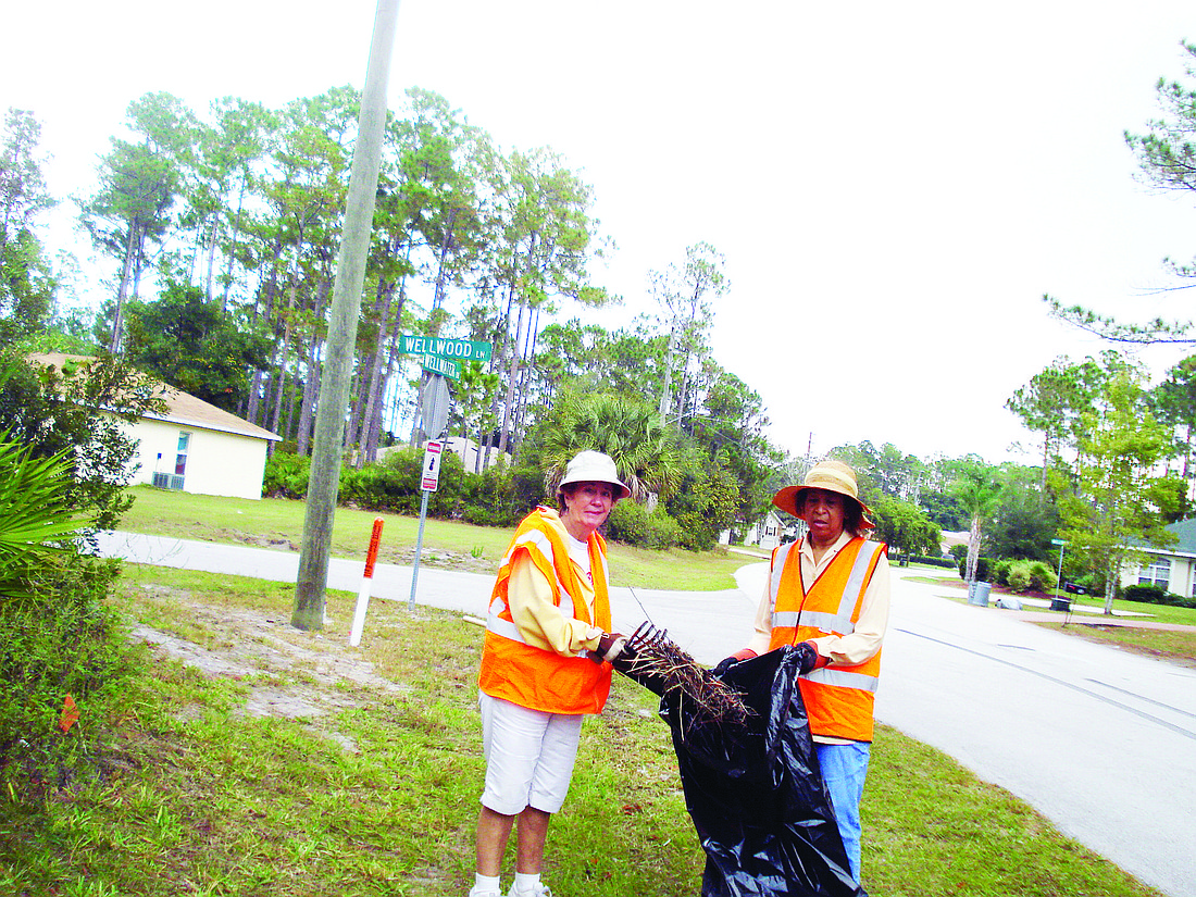Marge Collins and Wanda Christiani pick up trash on Wellwater Drive. COURTESY PHOTO