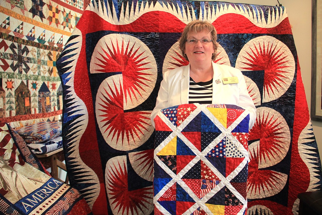 Terry Burtchell,Â Volusia County QOV group leader, surrounded by quilts for service members and veterans. Photo by Nichole Osinski