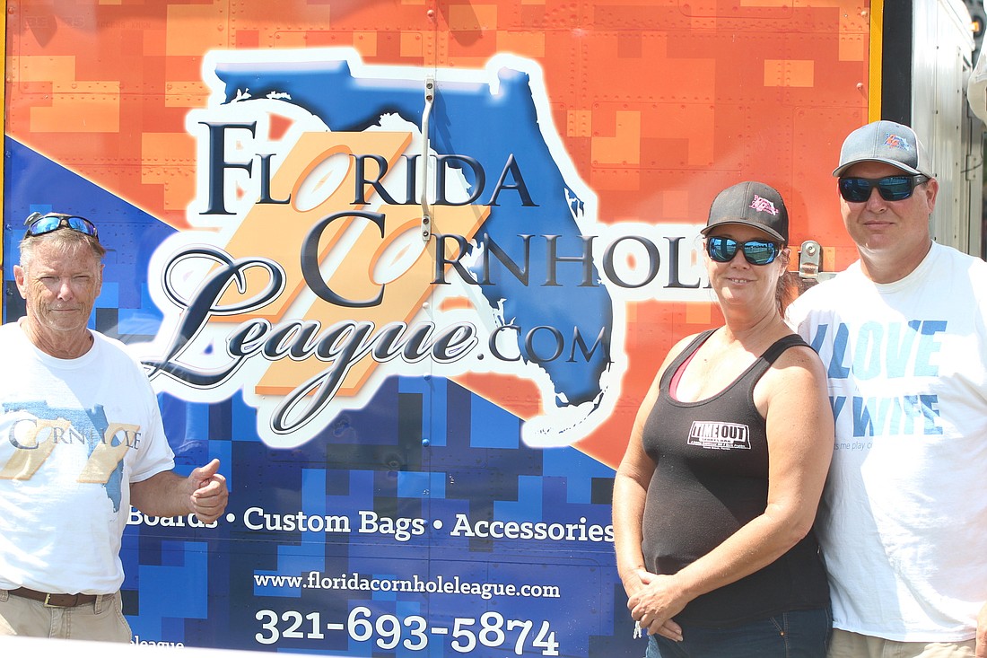 Founder Mike Barker's father Al Barker (left), Sandy Schmidt and Darrell Schmidt pose in front of the Florida Cornhole League trailer. Photo by Tim Briggs