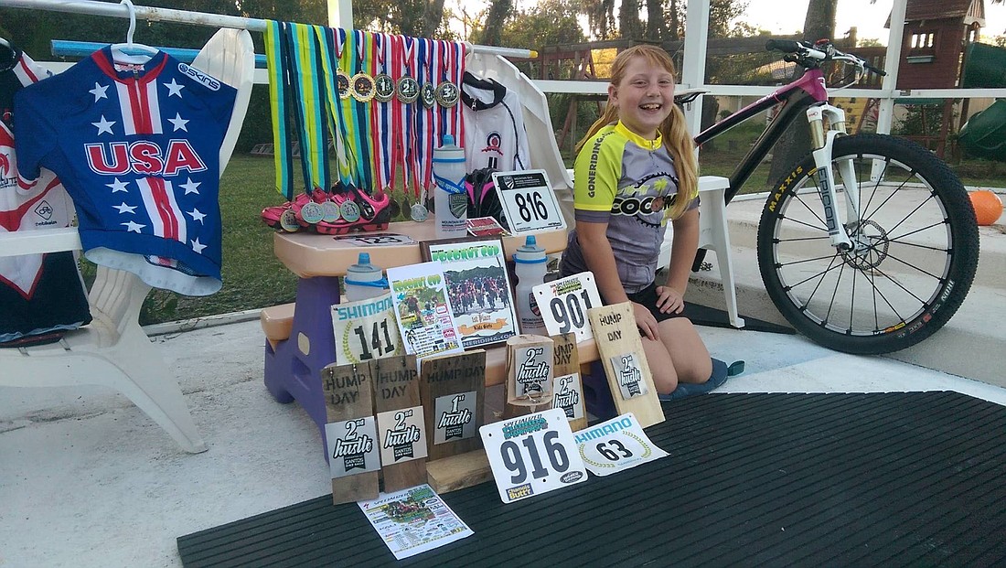 Rachel Hiller poses next to her medals at a race. Photo courtesy of Joe Hiller