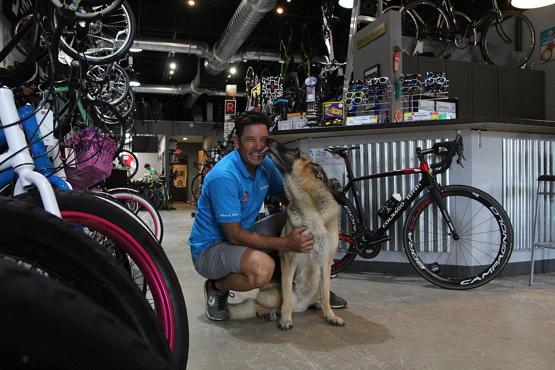 Steve Bodnaruk, owner of The Hub Cycling, gets a kiss from Lola, his dog and one of his best sales associates.