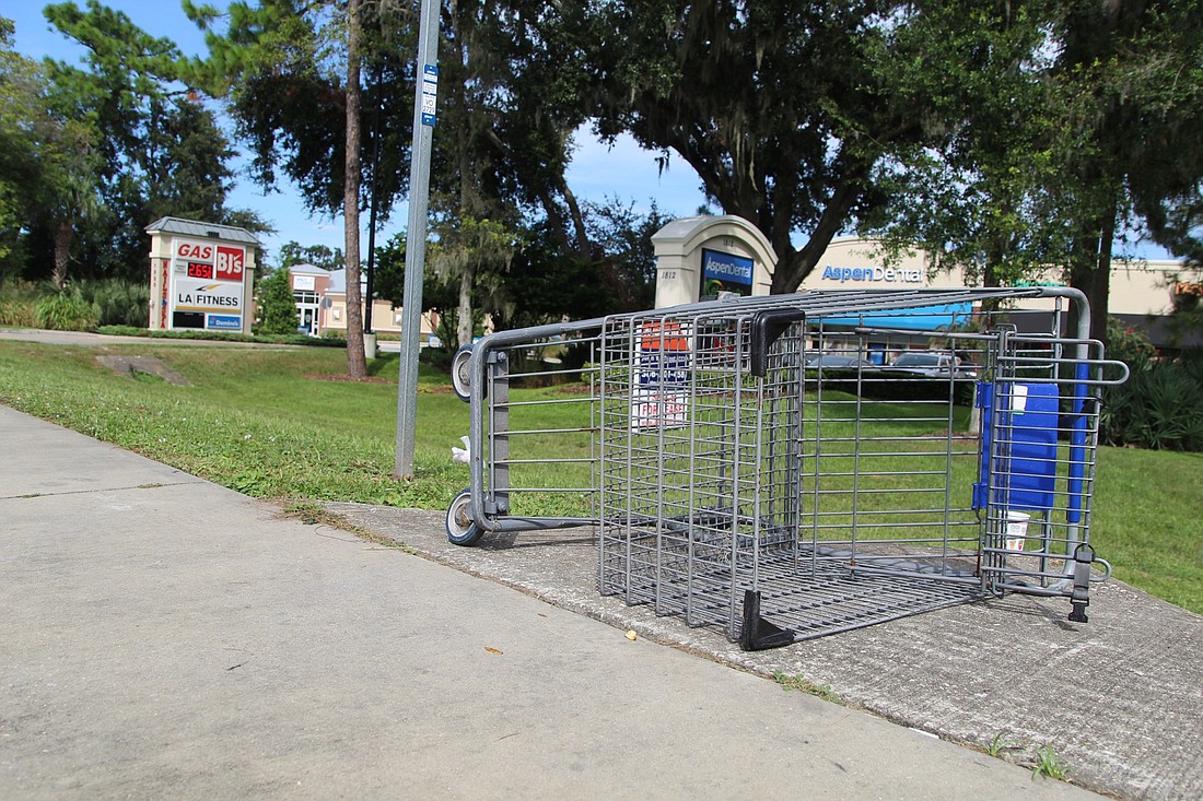 A shopping cart lays on its side beside a bus stop on Dunlawton Avenue. Photo by Lurvin Fernandez