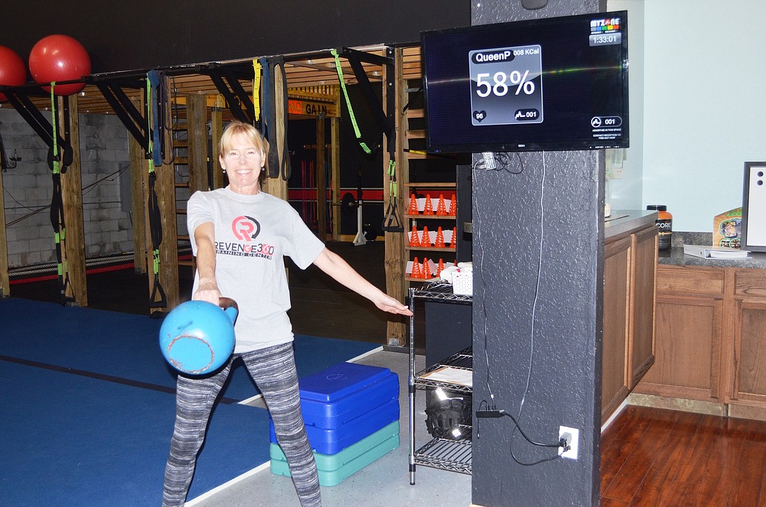 Patty Tremblay works out at Revenge 360 while a computer screen (upper right) shows her amount of effort by use of a MyZone monitor.