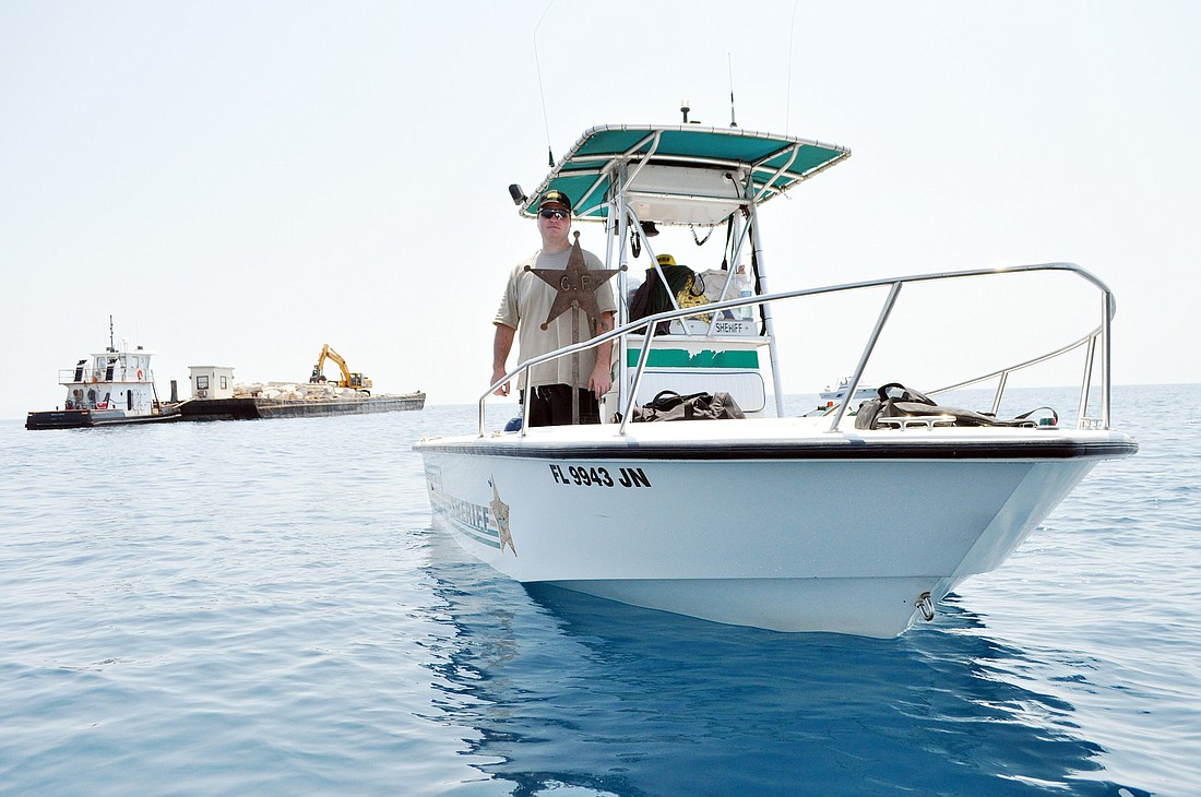 Jason Prather stands with a tribute to his father, Grady, while cement for the Grady Prather artificial reef is dropped July 21. PHOTO BY SHANNA FORTIER