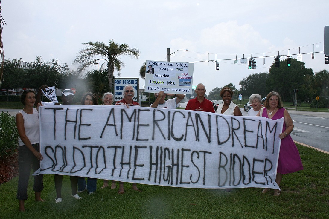 About a dozen people braved the rain to hold up protest signs Aug. 2, at Florida Park Drive and Palm Coast Parkway.