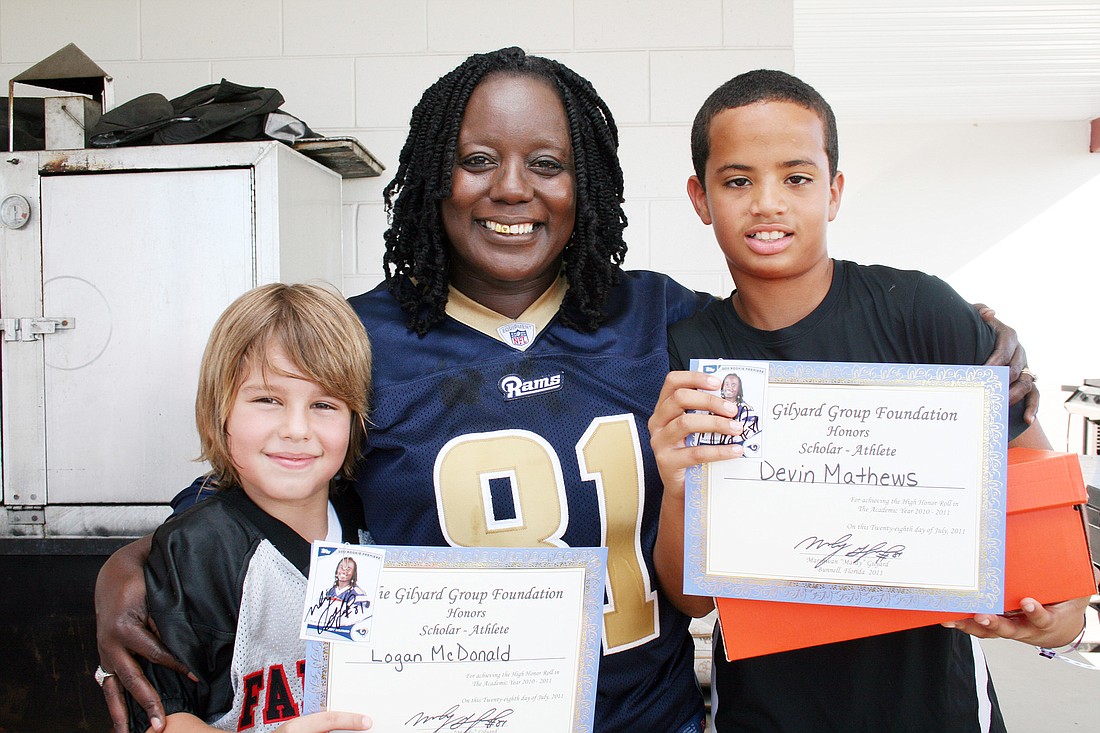 Mardy GilyardÃ¢â‚¬â„¢s mother, Trish Crudup, with cleats recipients Logan McDonald and Devin Mathews. PHOTO BY BRIAN MCMILLAN