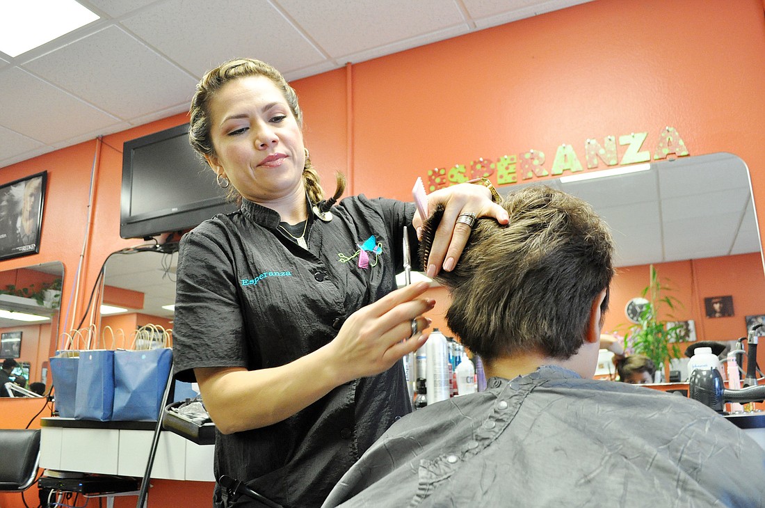 Esperanza Costa, owner of Sophisticated Hair Studio, gives one of 51 haircuts, Sunday, Aug. 31, to Flagler County children. PHOTO BY SHANNA FORTIER