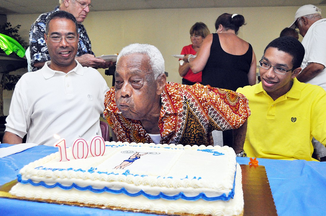 Ivan Heron, center, blows out the candles on his birthday cake with his son, Courtney Heron (left) and grandson, David Heron (right). COURTESY PHOTO
