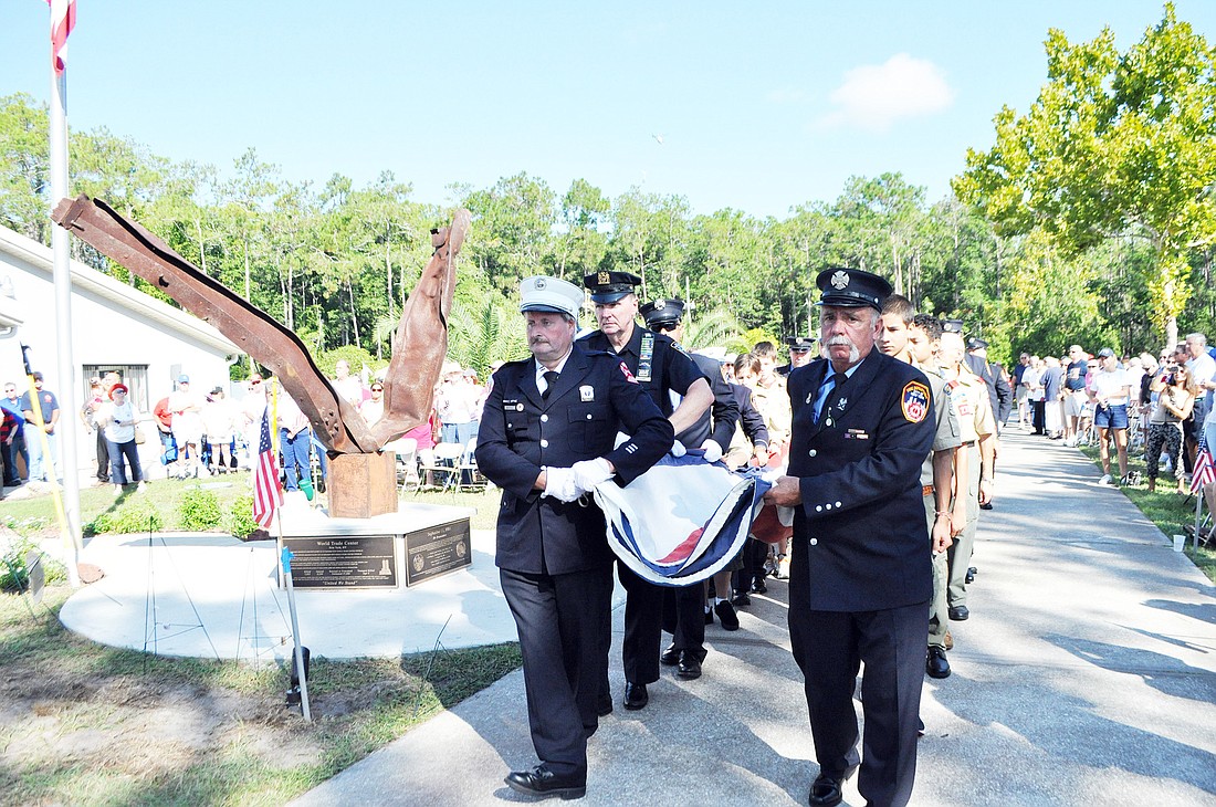 Retired New York firefighters and police officers carry the flag after revealing the Sept. 11 monument installed in front of the Elks Lodge. PHOTOS BY SHANNA FORTIER