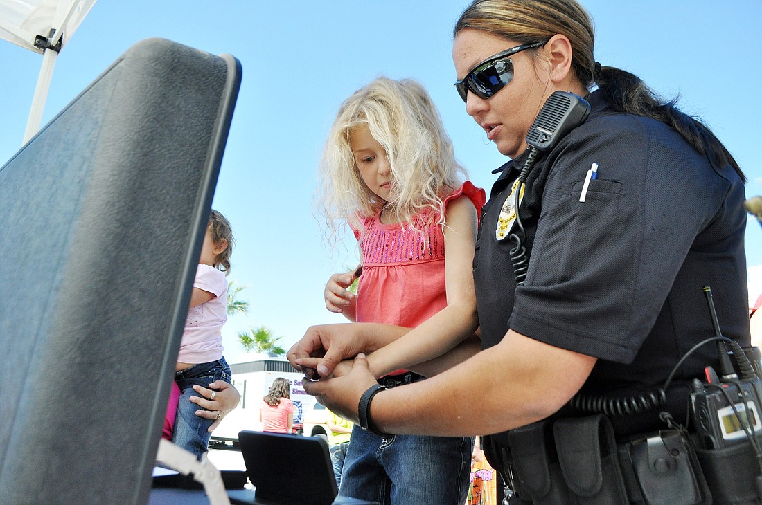 Hannele Walls-Sawchuk, 6, gets fingerprinted by Flagler Beach police officer Rossana Bustos. PHOTOS BY SHANNA FORTIER