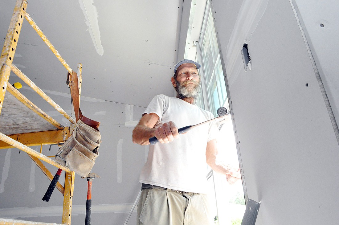Jeff Whelan, of Double J Drywall, hammers trim around the window frame Sept. 1, midway through the rebuild process. PHOTOS BY SHANNA FORTIER