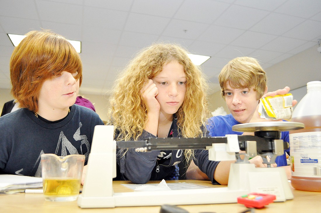 Kyle Huff, Matisse Feldman and Jacob Koch measure Italian dressing ingredients in the cooking lab, at Buddy Taylor Middle School. PHOTOS BY SHANNA FORTIER