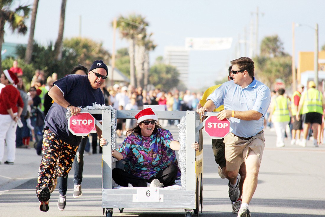 Mike DÃ¢â‚¬â„¢Ascheberg, Colleen Conklin and Trevor Tucker race down the street with their school-bus bed representing Flagler County Schools. PHOTOS BY SHANNA FORTIER