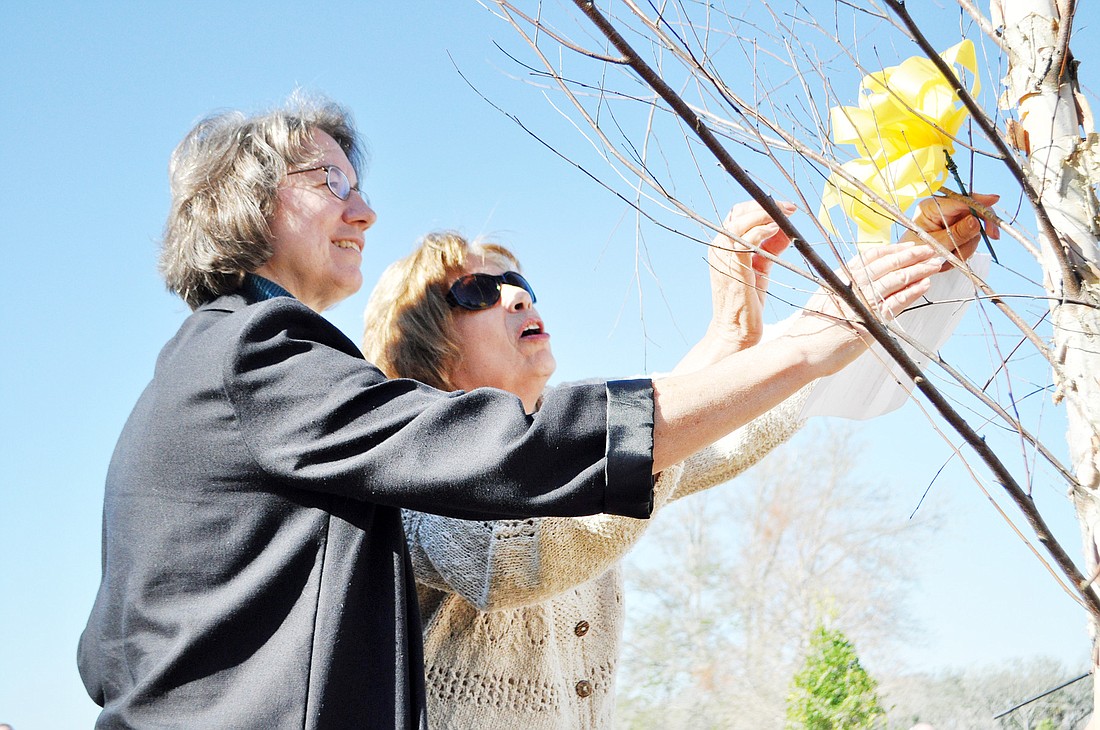 Deloris Ball, niece of both Hildegard Schwab and Margaret Davie, places a yellow ribbon on the tree for remembrance with the help of Terlizzo. PHOTOS BY SHANNA FORTIER