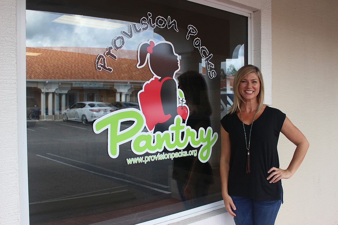 Carrie Torres, founder of Provision Pack Pantry, stands next to her program's logo on the outside of the pantry space in Ormond Beach. The logo reminds her of her youngest daughter Emma. Photo by Jarleene Almenas.