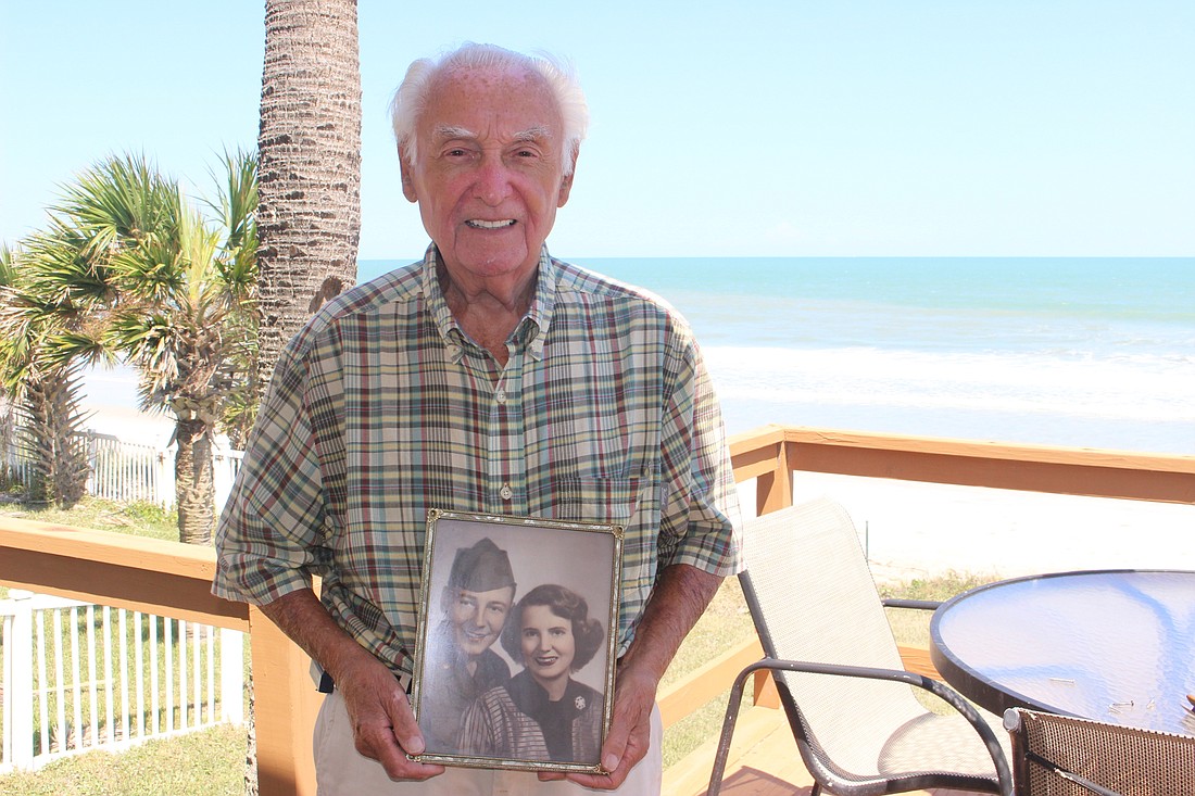 Russ Ackers, 88, stands on his balcony while holding a photo of he and his wife, Julie, after he came back from the Korean War. Photo by Jarleene Almenas
