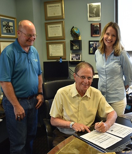 Werner Kruck, chief operating office and director,  President Locke Burt and  Melissa Burt DeVriese, chief administrative officer and chief legal counsel, sign the contract for the property. Photo courtesy of Security First