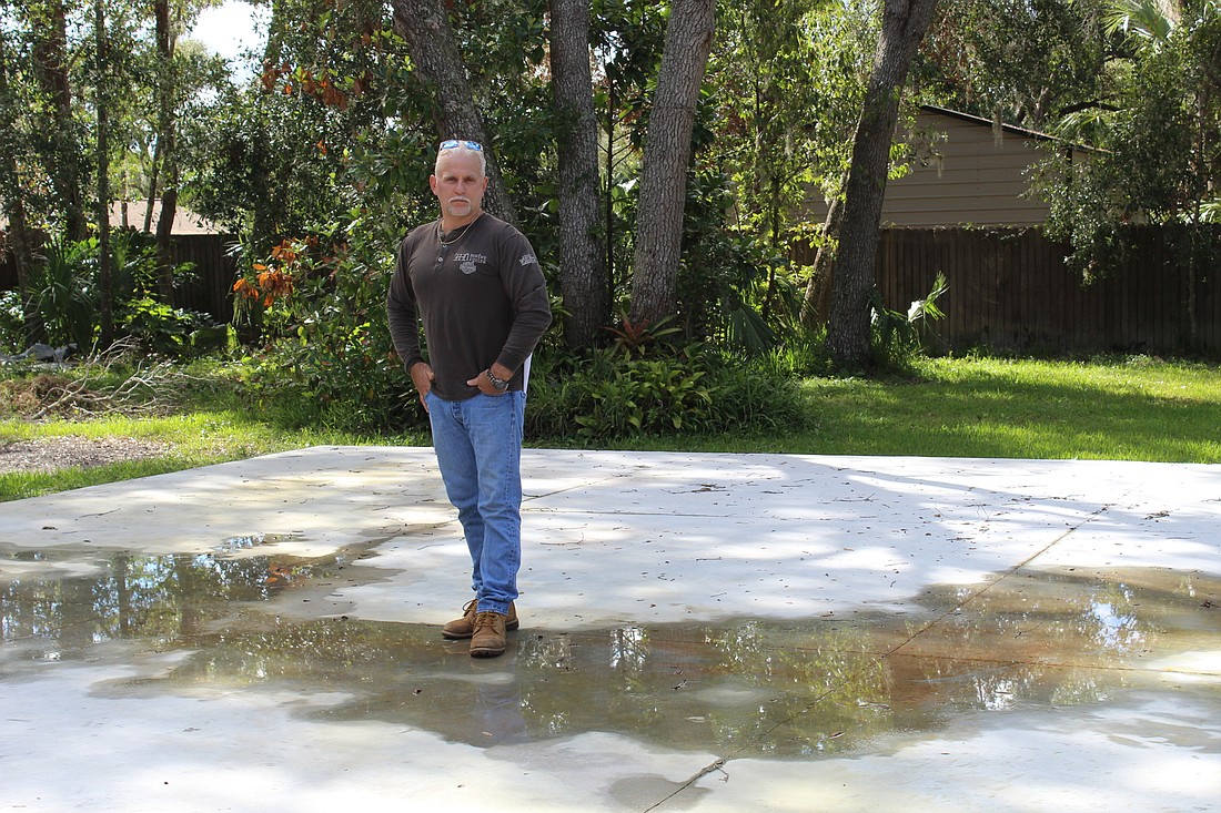 Cory Romaniuk stands in the middle of the concrete floor for a garage he'll have to wait months to built. Photo by Jarleene Almenas