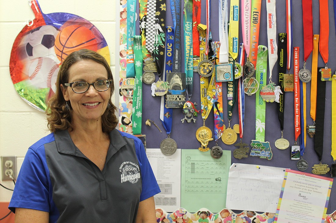 Janine Grover, Teacher of the Year nominee for Hinson Middle School, smiles besides her numerous running medals that she hopes inspires her students to continue to "run toward their goals." Photo by Jarleene Almenas