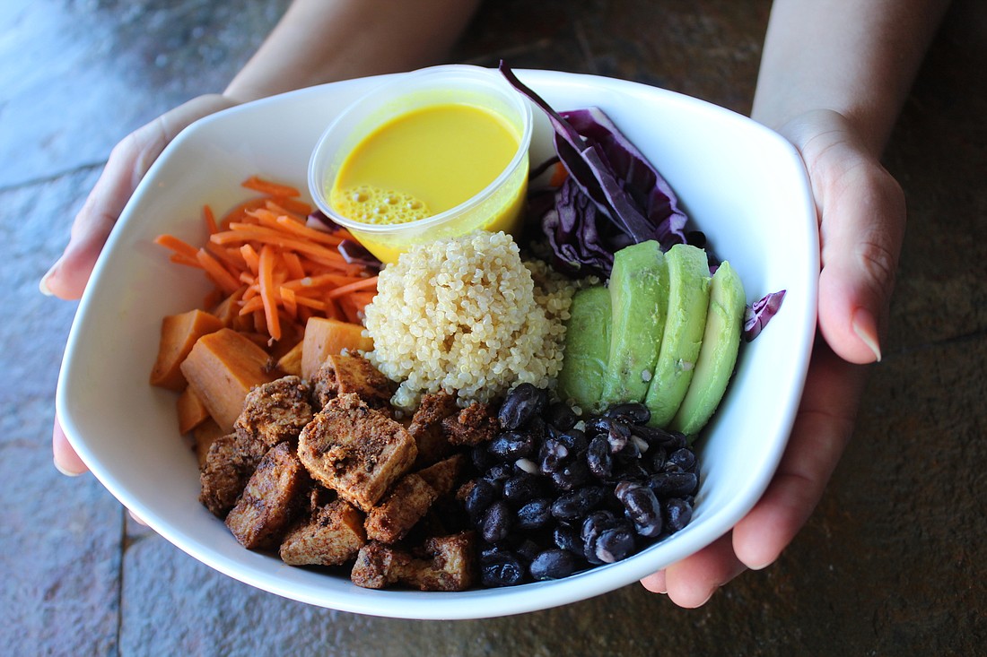 Wild Rabbit Bistro owner Laura Hannan holds Buddha Bowl, made with black beans, roasted roots, avocado, colorful veggies, seasonal greens, oil-free turmeric tahini dressing and with the option to add chicken, tofu or fresh salmon.