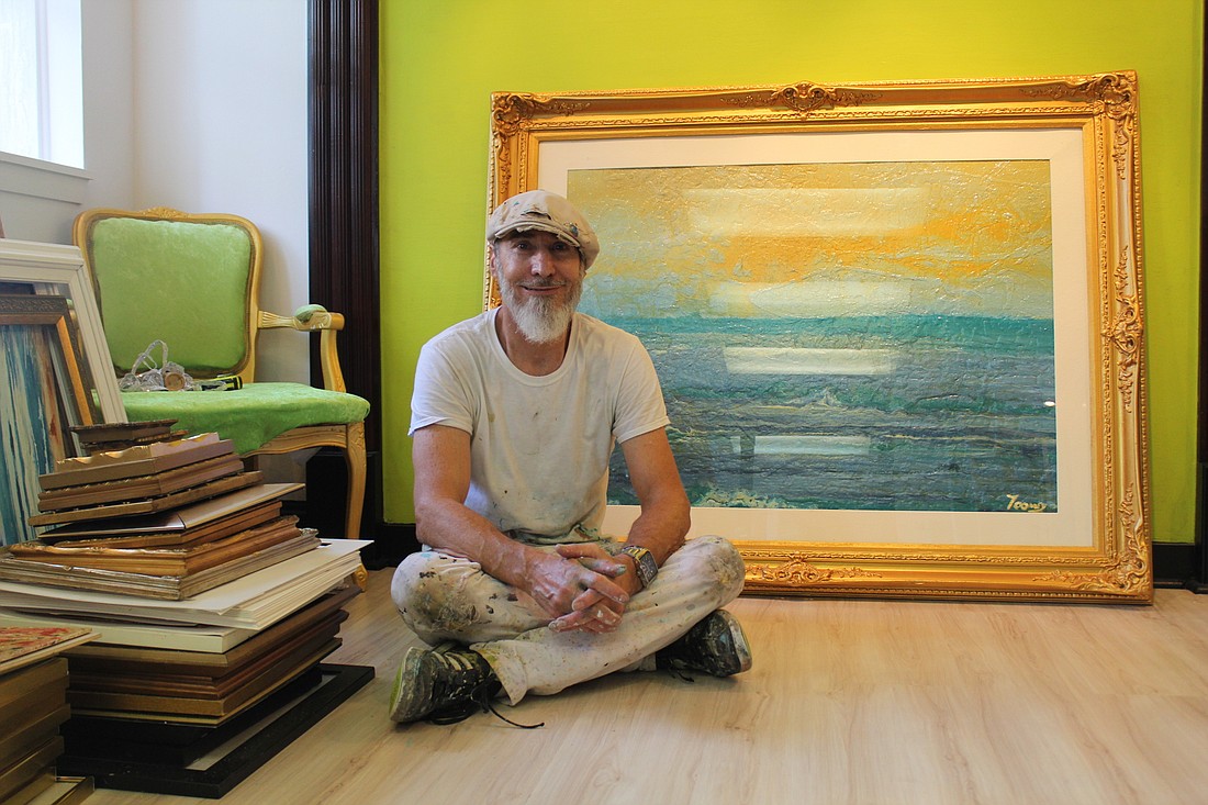 Artist Brent Toomey sits in front of his painting "New Day" in his new art gallery. This painting took him over 120 hours to complete. Photo by Jarleene Almenas