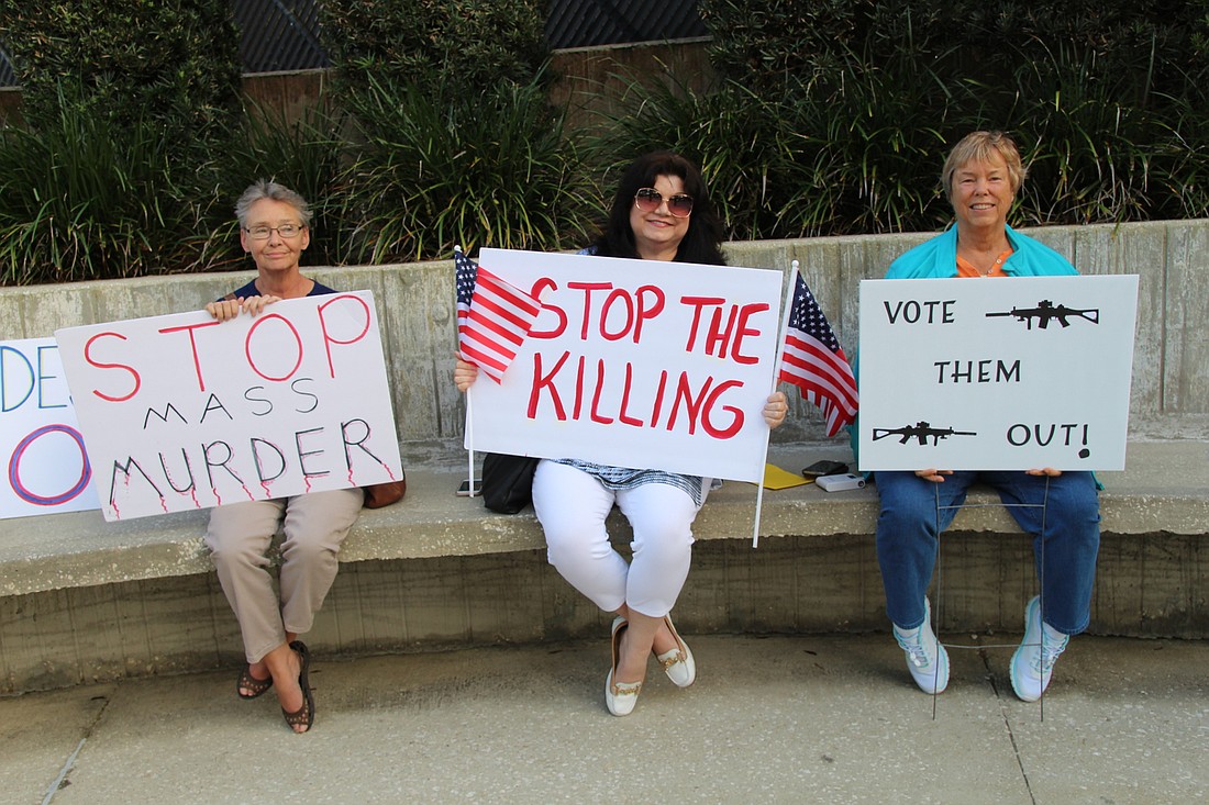 Port Orange resident Linda Michelini, and Deltona residents Cindy Carter and Carol Sheehan show their posters outside the Volusia County School Board complex before the meeting in DeLand on Tuesday, Feb. 27. Photo by Jarleene Almenas
