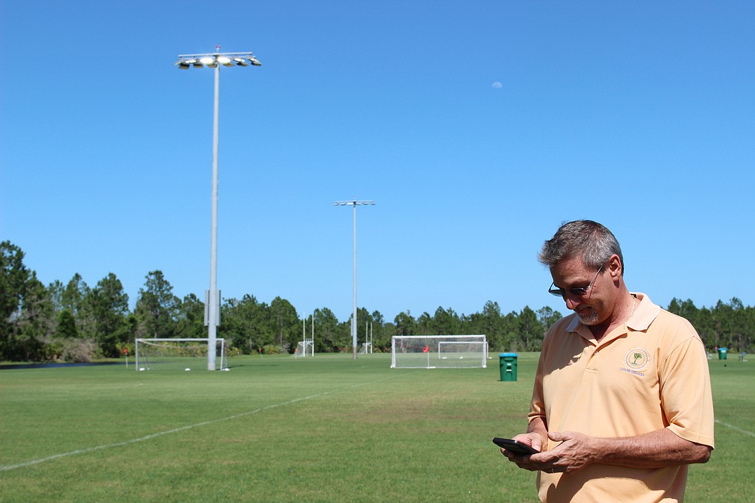 Ormond Beach Leisure Services Director Robert Carolin turns the lights on at a field inside the Ormond Beach Sports Complex with his cell phone. Photo by Jarleene Almenas