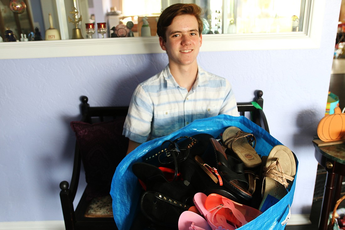Matthew Monroe holds up a bag of donated shoes in his Ormond Beach home. Photo by Jarleene Almenas