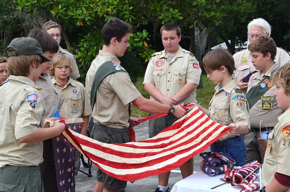 Scouts cut stripes from the flag for participants to lay on the fire. Shown are Bryce Wooten, Wyatt Reynolds, Jeffrey Serle, Sam Laughlin, Hunter Chewning, Chase Mott, Alex Swindle, Logan Treglia, Logan Littell, Chris Jessup and Keanon Jessup.