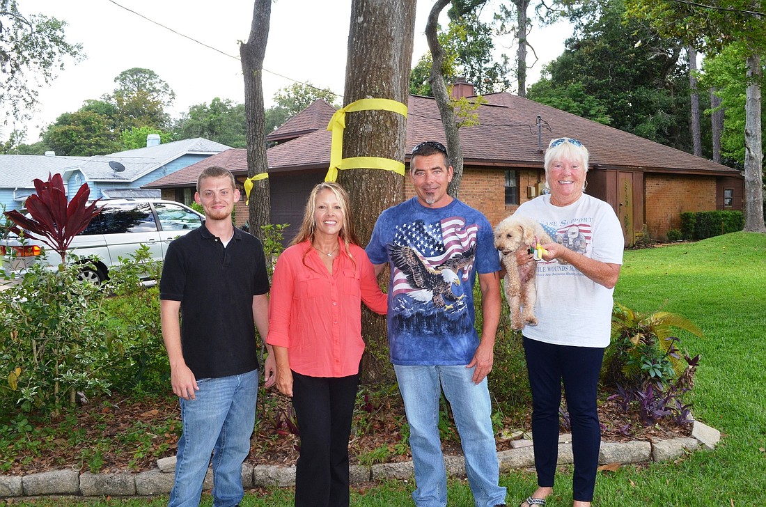 Travis Miller, Amanda Rocke, Sean Rocke and Janie Rocke stand in front of one of the yellow ribbons on Stratford Place. The dog is Rags.Photo by Wayne Grant