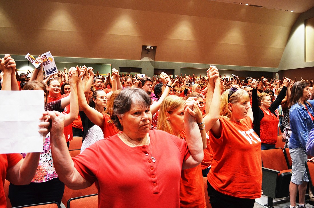 Teachers stand to show solidarity during the meeting on the contract.Photo by Wayne Grant