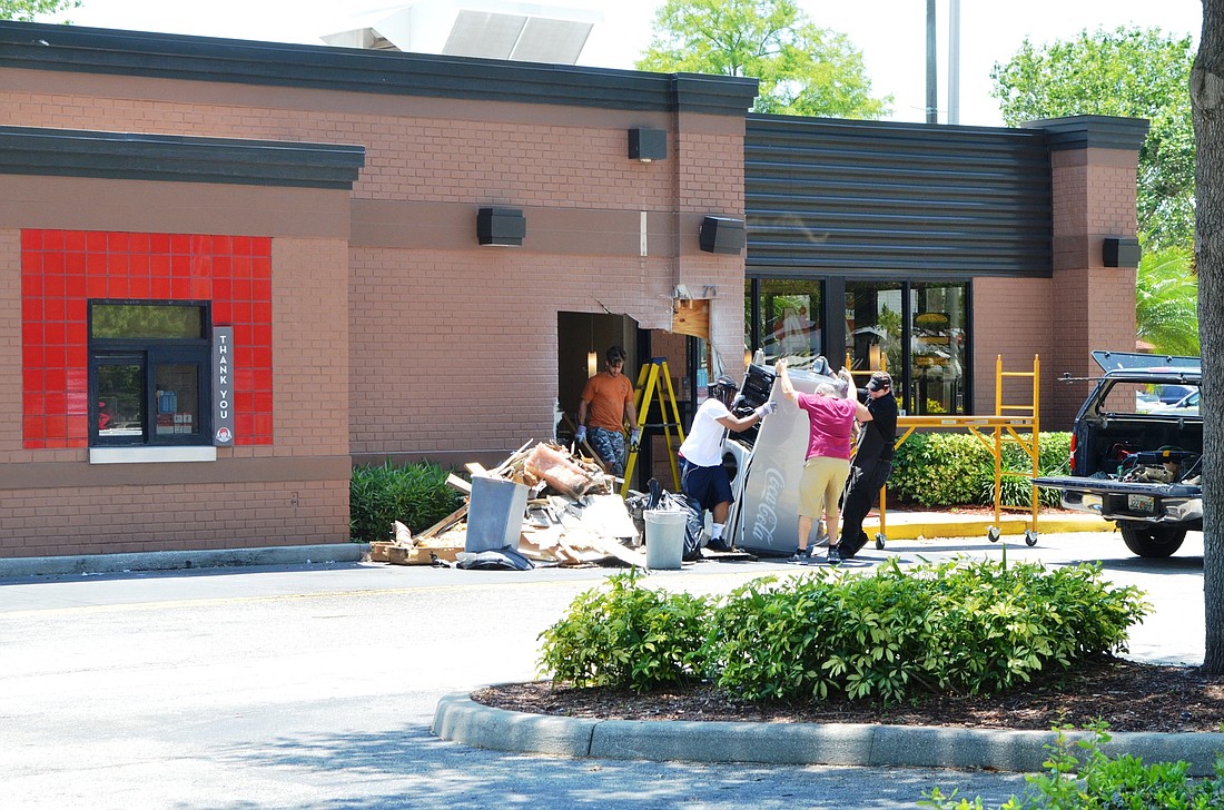 Workmen remove equipment from Wendy's Restaurant May 25 after a car crashed into the building earlier that morning resulting in the death of an Ormond Beach man. Photos by Wayne Grant