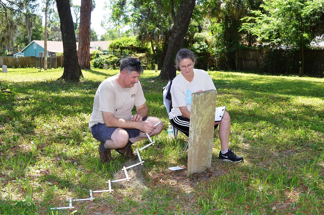 Tom and Sandy Hall, scout parents, record the words on a tombstone.