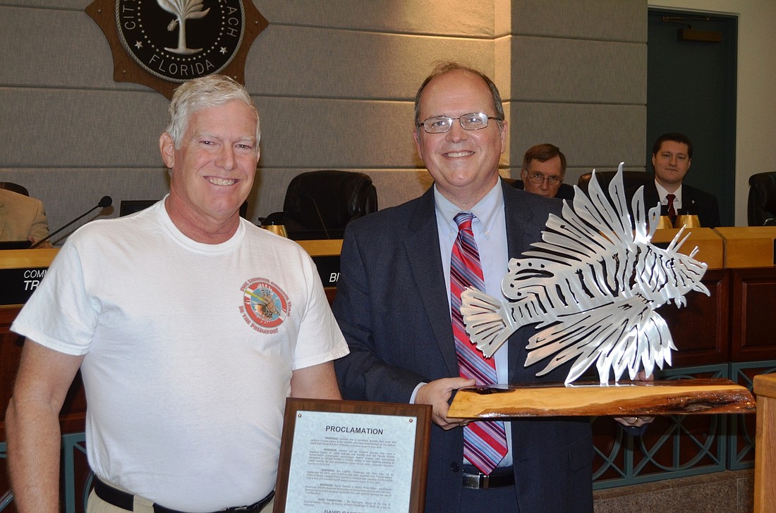 Dave Garrett received a proclamation from the City Commission for being named Lion Fish King. Mayor Bill Partington holds the trophy Garrett received in the competition.