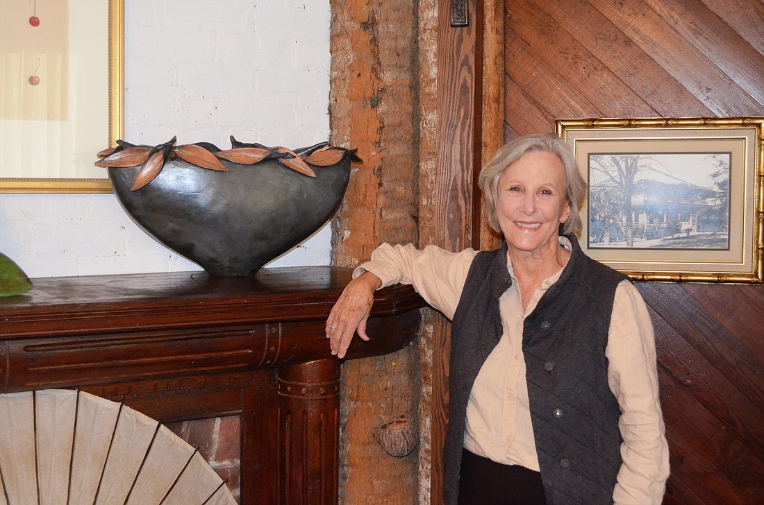 Sang Roberson stands in her palm log cabin where some of her art is displayed.