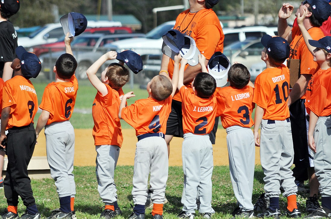 Young baseball players wave their hats in appreciation Saturday, March 3, during a flyover performed by Blue Sky Yakrobatics. PHOTOS BY SHANNA FORTIER