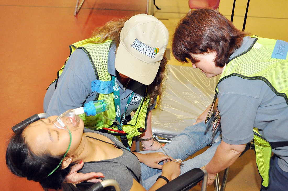 Jennifer Idica plays a diabetic patient who has become unresponsive during a mock emergency shelter activity. Diane Greenhalgh and Susan Welsh participate as nurses.
