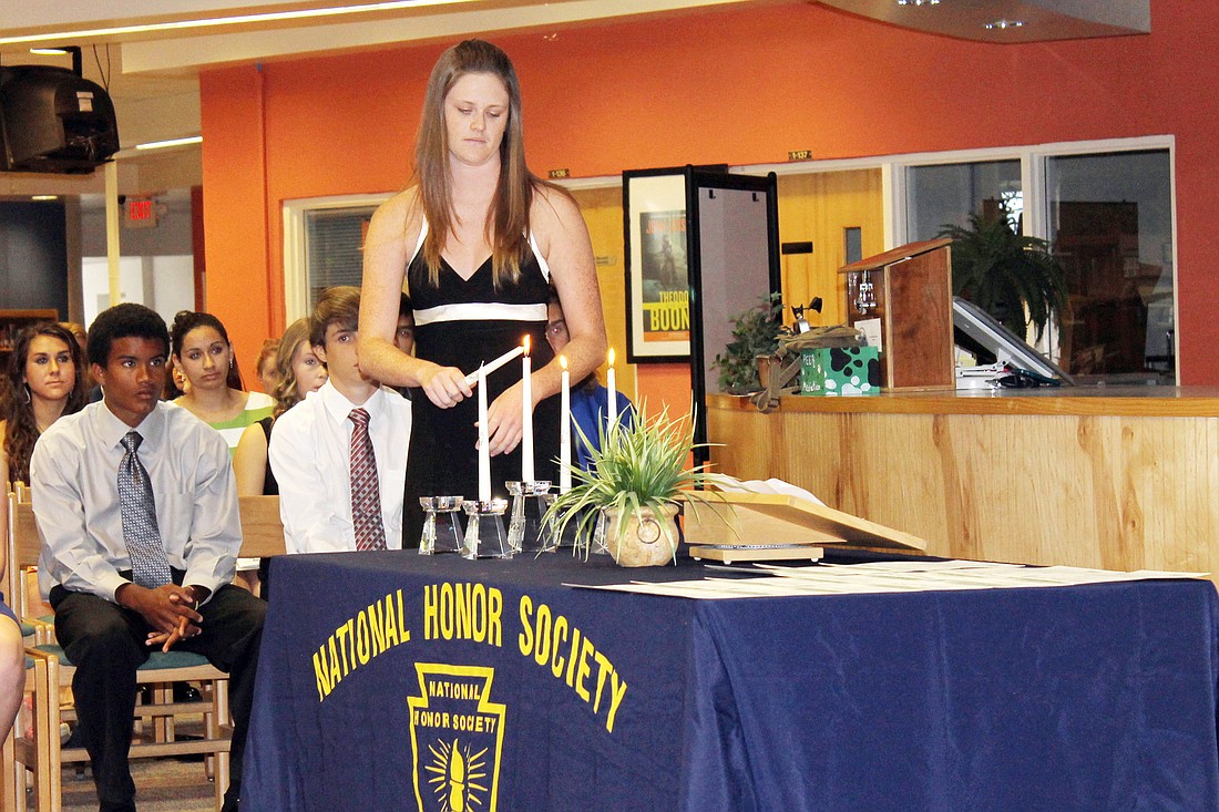 NHS Secretary Kaitlyn Sanson participates in the candle lighting ceremony after reading her speech on service, one of the four qualities the National Honor Society was founded upon. COURTESY PHOTO