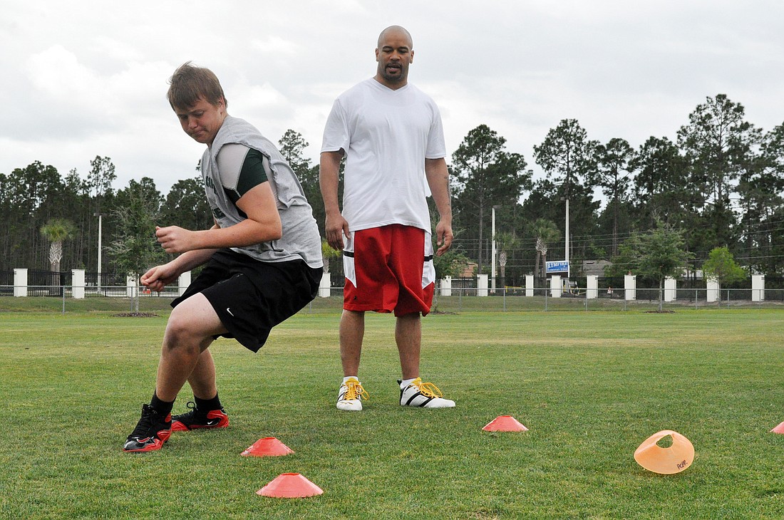 Troy Ailes, 16, plays football at Flagler Palm Coast High School. Here, he does footwork drills Saturday, April 14, as NFL linebacker Larry Foote observes.