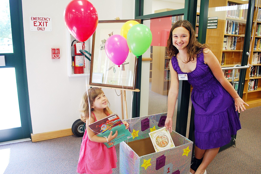 Lorelei DeLorenzo helps Sarah Dewitz, founder of Just 1 Book, place the first donated books into the libraryÃ¢â‚¬â„¢s collection box. COURTESY PHOTO