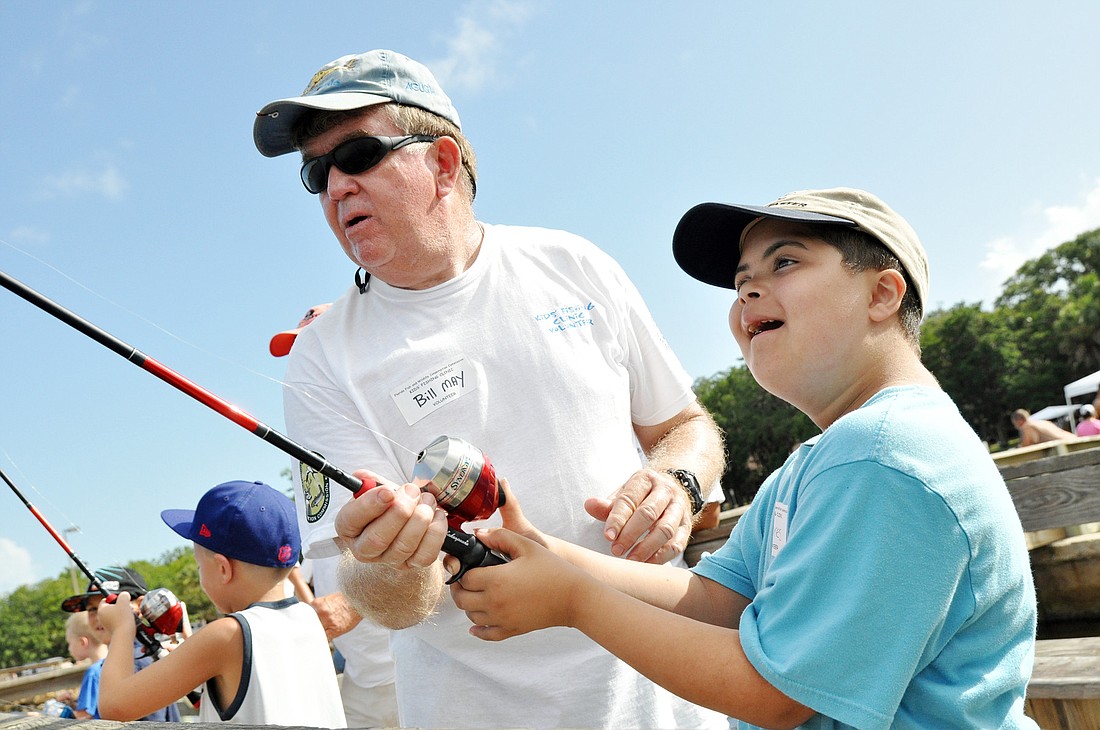 Sport Fishing Club member Bill May teaches Tavares Wilcox how to cast a line Saturday, July 14, at the clubÃ¢â‚¬â„¢s kids fishing clinic held at Bings Landing.