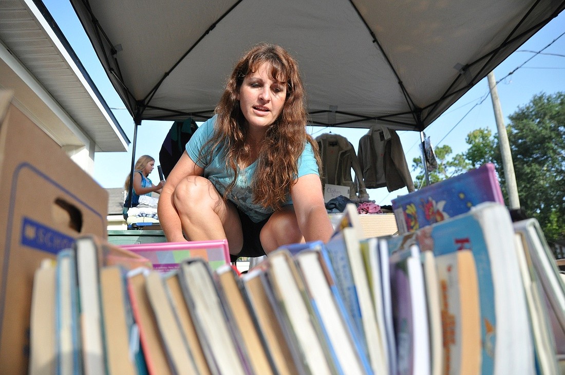 Cara Cronk finishes placing items in her driveway Friday, July 27, for the garage sale she hosted to raise money for her daughter's trip.