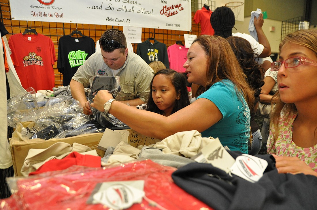 Jeanne Pajak and her daughter, Jinelle, sort through boxes of polo T-shirts Saturday, Aug. 4, at the U-Name It booth during the Back to School Jam.