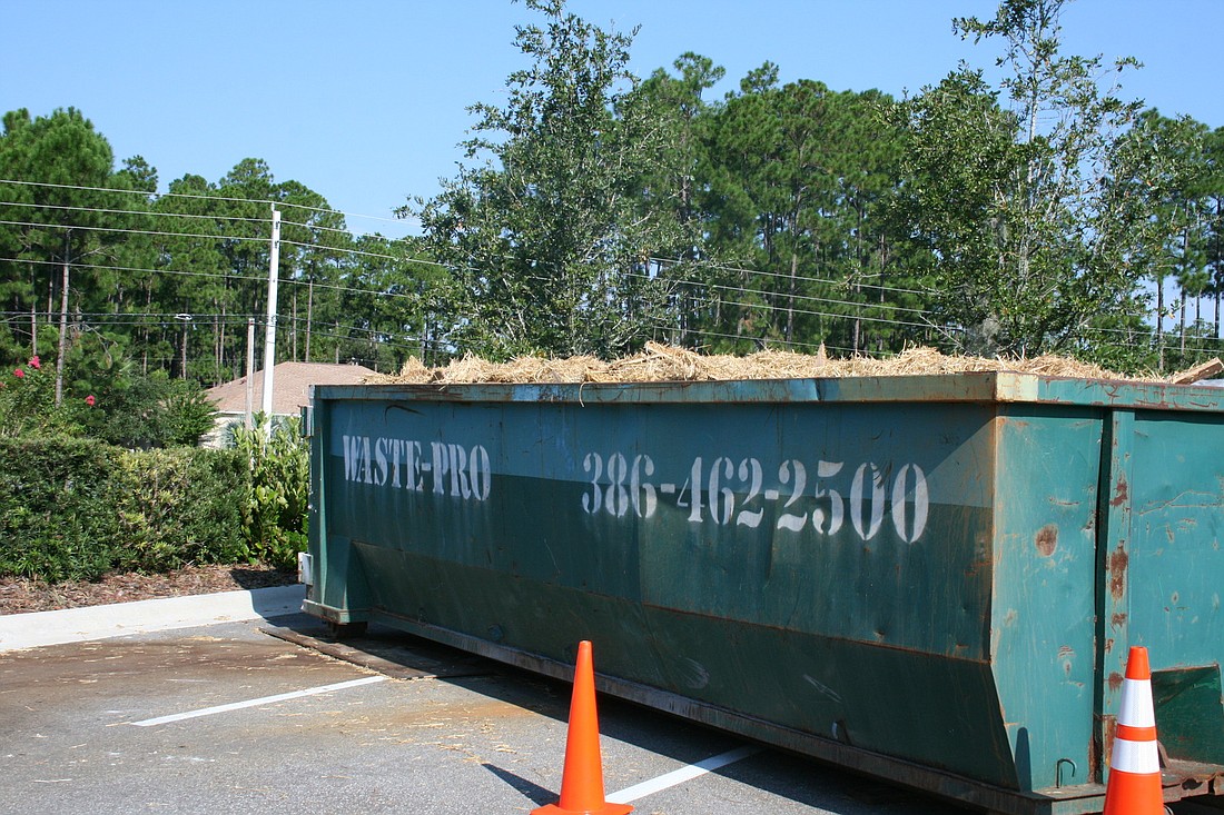 A Dumpster in the Wells Fargo parking lot is full of hay removed from the building's walls.