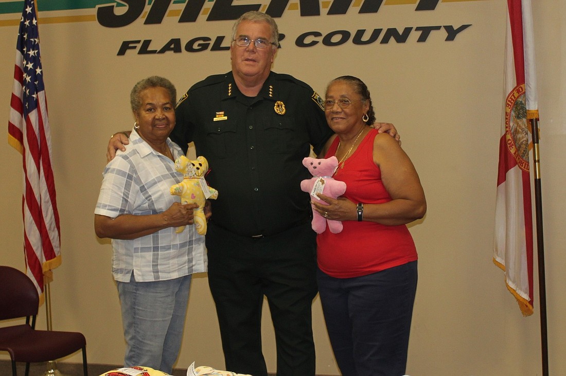Flagler County Sheriff Donald Fleming accepts the teddy bears from Greta Hogart (left) and Audrey Williams. COURTESY PHOTO